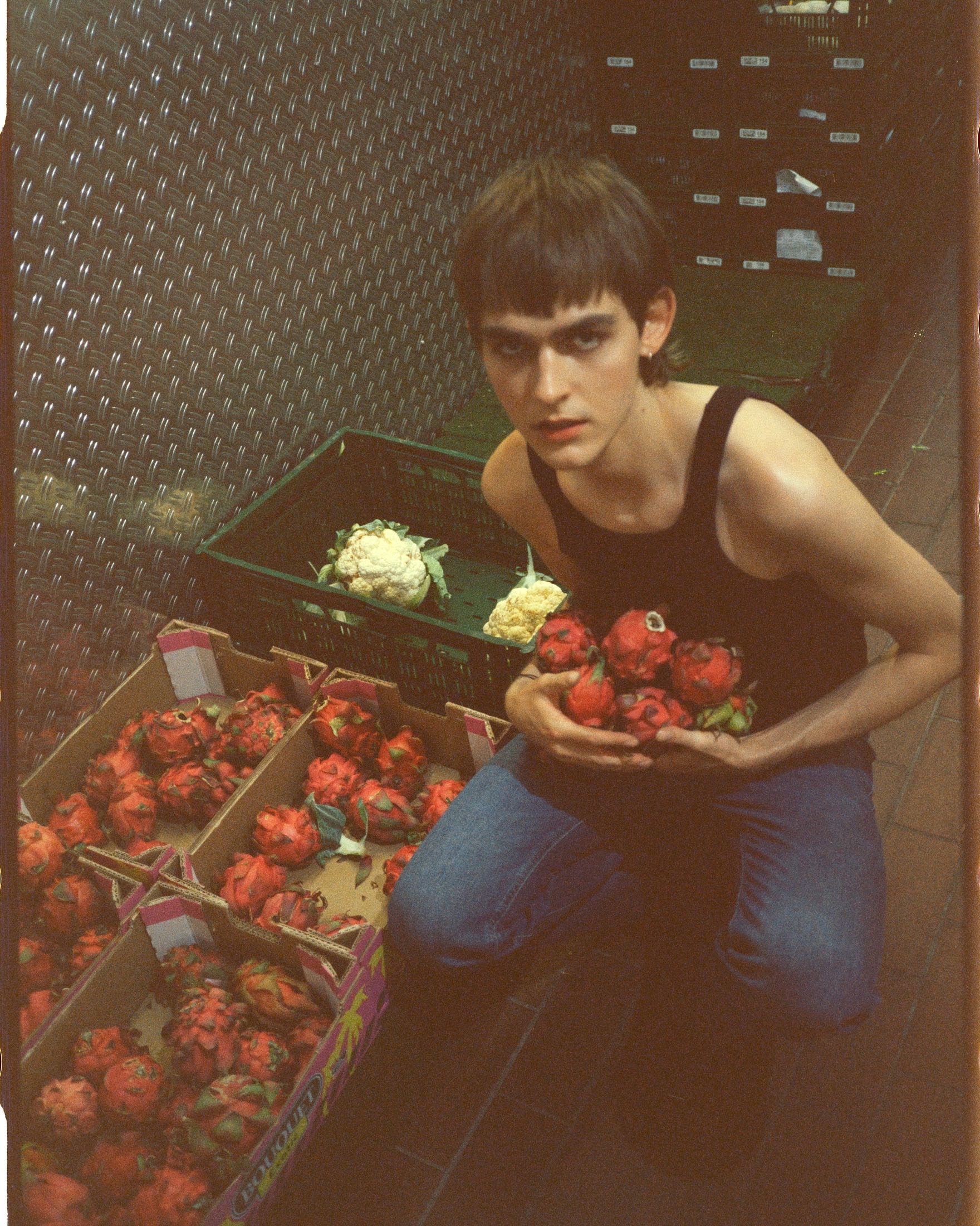 Modell an einem Marktstand mit Kisten voller Erdbeeren