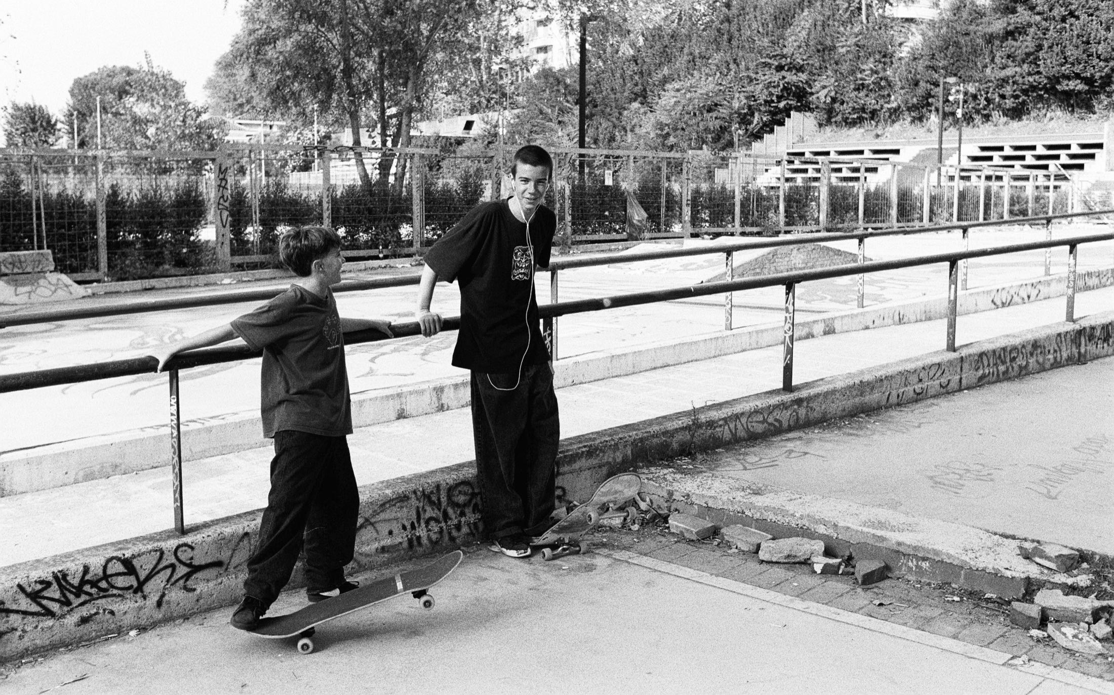 Zwei Skater stehen an einem Geländer, weite Aufnahme des Platzes