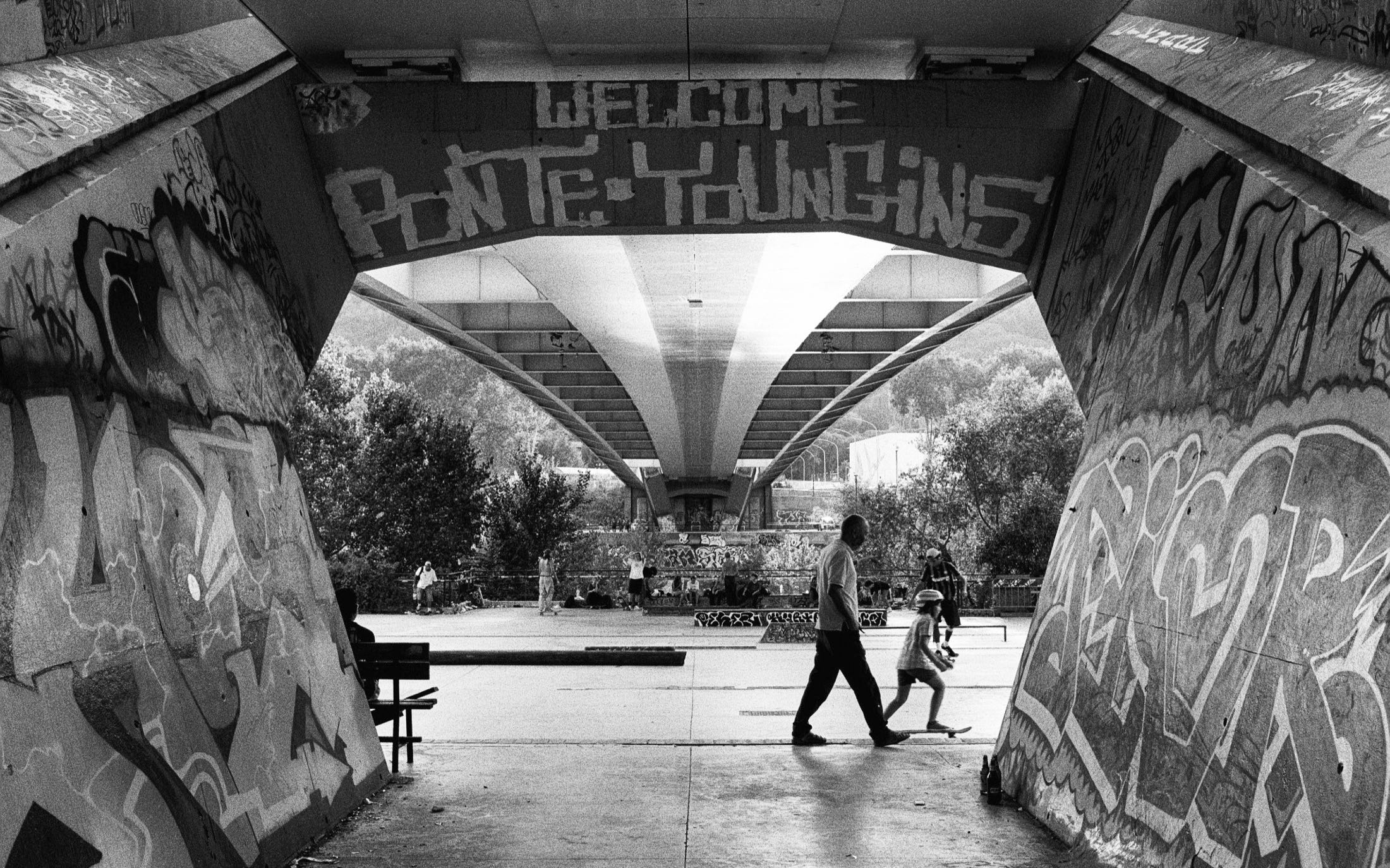 Blick durch einen Graffiti-Durchgang mit dem Schriftzug Welcome Ponte auf den Platz
